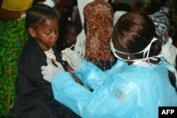 FILE - A Cameroonian nurse gives an injection to a girl arriving with her familly after spending several months in Libya, at the Yaounde International Airport in Cameroon, Nov. 22, 2017.