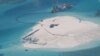 FILE - In this photo taken by surveillance planes and released May 15, 2014 by the Philippine Department of Foreign Affairs, a Chinese vessel, top center, is used to expand structures and land on the Johnson Reef at the Spratly Islands in the South China Sea, Philippines. 