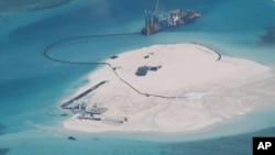 FILE - In this photo taken by surveillance planes and released May 15, 2014 by the Philippine Department of Foreign Affairs, a Chinese vessel, top center, is used to expand structures and land on the Johnson Reef at the Spratly Islands in the South China Sea, Philippines. 