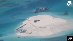 FILE - A Chinese vessel, top center, is used to expand structures and land at the Spratly Islands in the South China Sea in this Feb. 25, 2014, photo. U.S. officials oppose Beijing's massive island-building, but say deployment of advanced missiles further demonstrates China's intent.