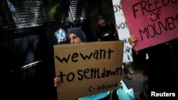 A Syrian refugee holds a banner during a demonstration outside the German embassy against delays in reunifications of refugee families from Greece to Germany, in Athens, Greece, Aug. 2, 2017. 