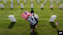 In preparation for Memorial Day, Boy Scout Guadalupe Gomez helps place U.S. flags at Fort Sam Houston National Cemetery in San Antonio, Texas, on May 23, 2014.