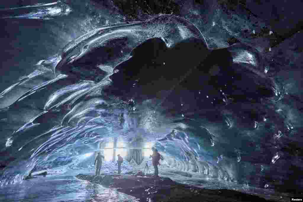 People stand in the Mill, a 20-meter-long natural ice cave, at the Glacier 3000 ski resort in Les Diablerets, Switzerland.