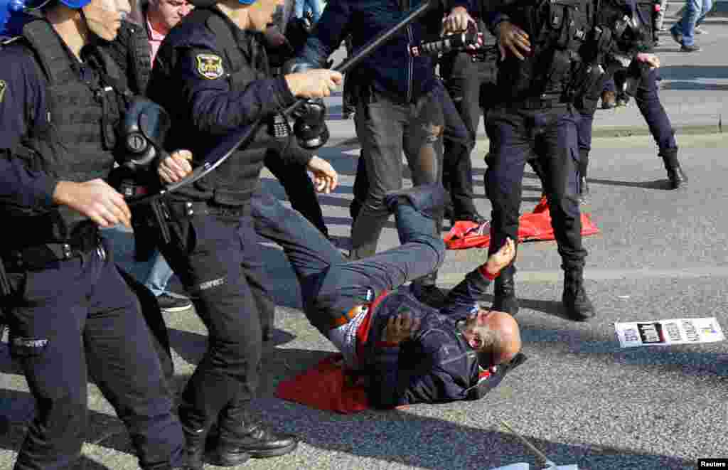 برخورد بین پلیس ضد شورش با یک معترض در آنکارا، ترکیه. معترضان برای یادبود کشته شدگان بمب گذاری انتحاری پارسال در آنکارا جمع شده بوده اند.