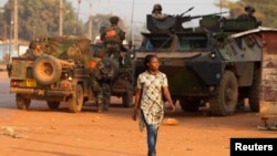 A woman walks past French peacekeeping troops in a street of the capital Bangui, Central African Republic, Jan. 17, 2014.