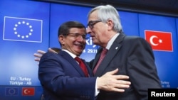 Turkish Prime Minister Ahmet Davutoglu (L) and European Commission President Jean Claude Juncker (R) greet each other after a news conference following a EU-Turkey summit in Brussels, Belgium, Nov. 29, 2015.
