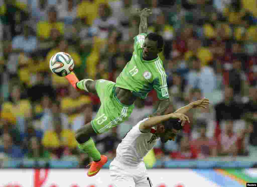 Nigeria&#39;s Juwon Oshaniwa (L) jumps for the ball with Iran&#39;s Reza Ghoochannejhad during their 2014 World Cup Group F soccer match at the Baixada arena in Curitiba, June 16, 2014.
