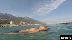 FILE - Victor floats in the sea as he spends a day at Coral beach, La Guaira, near Caracas, Venezuela, March 23, 2019. 
