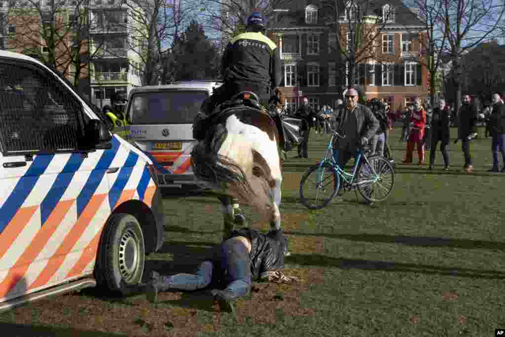 A woman gets trampled by a police horse during a demonstration of several hundreds of people protesting against the coronavirus lockdown and curfew in Amsterdam, Netherlands.