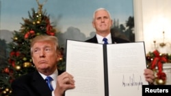 Presiden AS Donald Trump memegang proklamasi yang ia tandatangani yang menyatakan Amerika Serikat mengakui Yerusalem sebagai ibukota Israel dan akan memindahkan kedutaan besarnya ke Yerusalem, setelah selesai menyampaikan pidato di Gedung Putih di Washington, 6 Desember 2017.