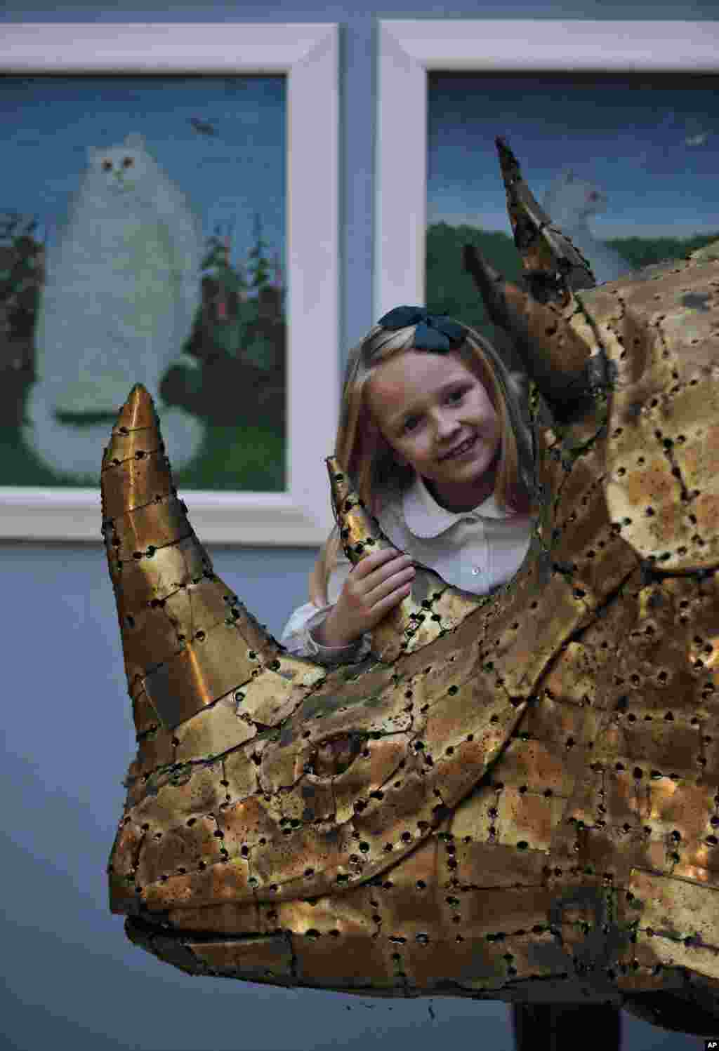 Une fille caresse une sculpture de bronze représentant un rhinocéros lors d&#39;une vente aux enchères sur le thème que propose l&#39;animal dans l&#39;inspiration artistique de presse, intitulé les &laquo;créatures grandes et petites, à Londres, le lundi 15 décembre 2014