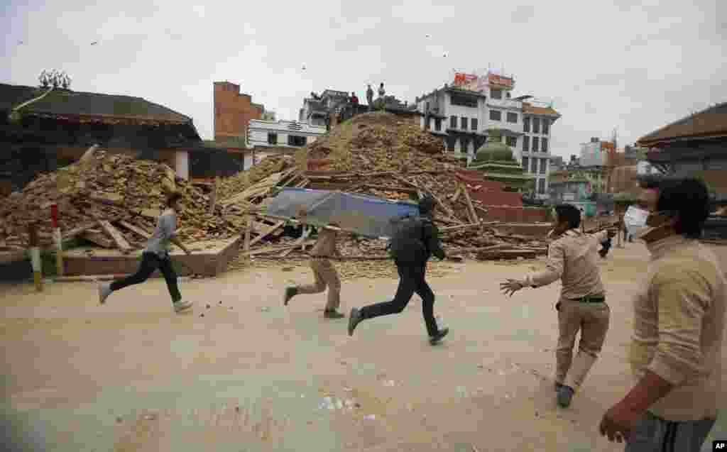 Volunteers run with a stretcher to carry a dead body recovered from the debris of a building that collapsed after an earthquake in Kathmandu, Nepal, Saturday, April 25, 2015.