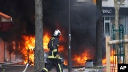 Un pompier passe devant des voitures en flammes lors du traditionnel rassemblement du 1er mai à Paris, France, le 1er mai 2018.