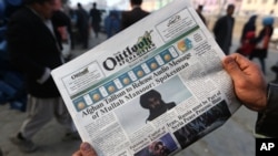 FILE - An Afghan man reads a local newspaper with photos of Afghan Taliban leader Mullah Akhtar Mansour, in Kabul, Afghanistan, Dec. 6, 2015. The U.S. military said a drone strike Friday has likely killed Mansoor in a remote area of Pakistan near Afghanis
