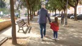 A young girl walks with her elderly grandparent along a tree-lined street in Rome, Italy, March 5, 2020. (AP Photo)
