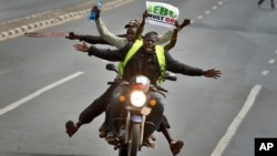Une moto transporte un manifestant portant un panneau indiquant l'acronyme de la commission électorale nationale, à Nairobi, Kenya, le 6 juin 2016.
