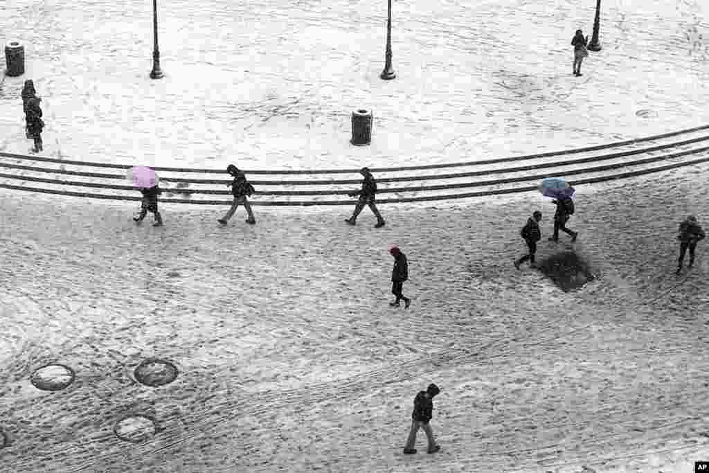 Para pejalan kaki melintasi Union Square yang becek dengan salju di New York City. Badai musim dingin kembali melintasi bagian timur laut Amerika, setelah temperatur sempat menghangat di akhir pekan.