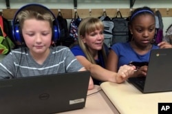 FILE - Fifth grade teacher Heather Dalton, center, works with students Julian Ryno, left, and Ma'Kenley Burns, doing math problems on the DreamBox system at Charles Barnum Elementary School in Groton, Connecticut, Sept. 20, 2018.