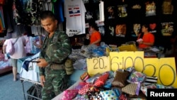 Thailand's junta kept many of the thousands of troops and police off the streets as the number of people making a public show of dissent to the May 22 coup dwindled. A soldier stand guards at a shop at Chatuchak market in Bangkok, Thailand, June 8, 2014.