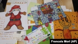 Envelopes addressed to "Pere Noel" - Father Christmas in French - decorated with love hearts, stickers and glitter, are displayed by postal workers in Libourne, southwest France, Monday, Nov. 23, 2020. (AP Photo/Francois Mori)