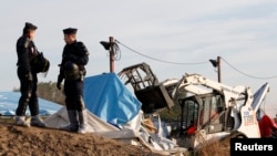 French CRS riot police secure the area as a bulldozer tears down makeshift shelters during the dismantlement of the camp called the "Jungle" in Calais, France, Oct. 27, 2016.