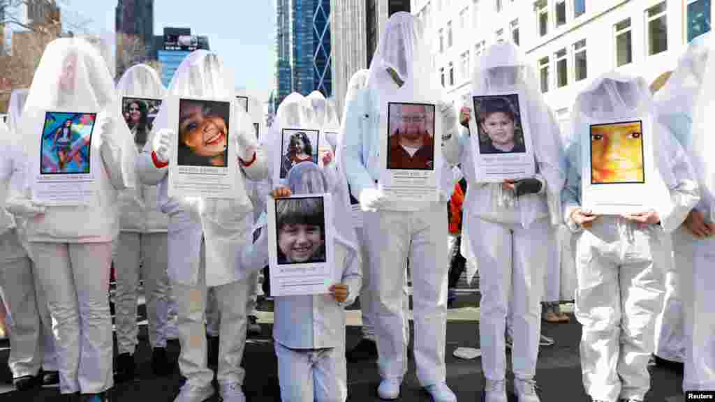 在紐約市參加遊行的人士手持校園槍擊遇難者的照片