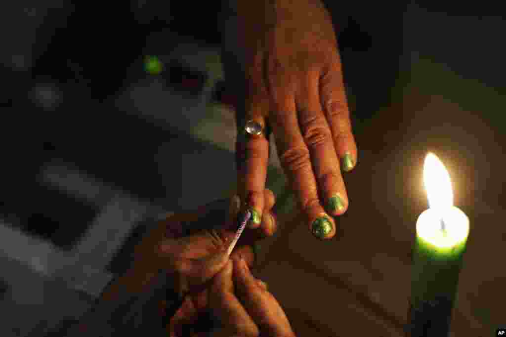 A polling official ink-marks the index finger of a female voter during the sixth phase of polling of the Indian parliamentary elections in Gauhati, India.