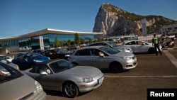 A Gibraltarian police officer guides drivers as they wait in line to enter Spain at its border with the British colony of Gibraltar in Gibraltar, July 29, 2013. 