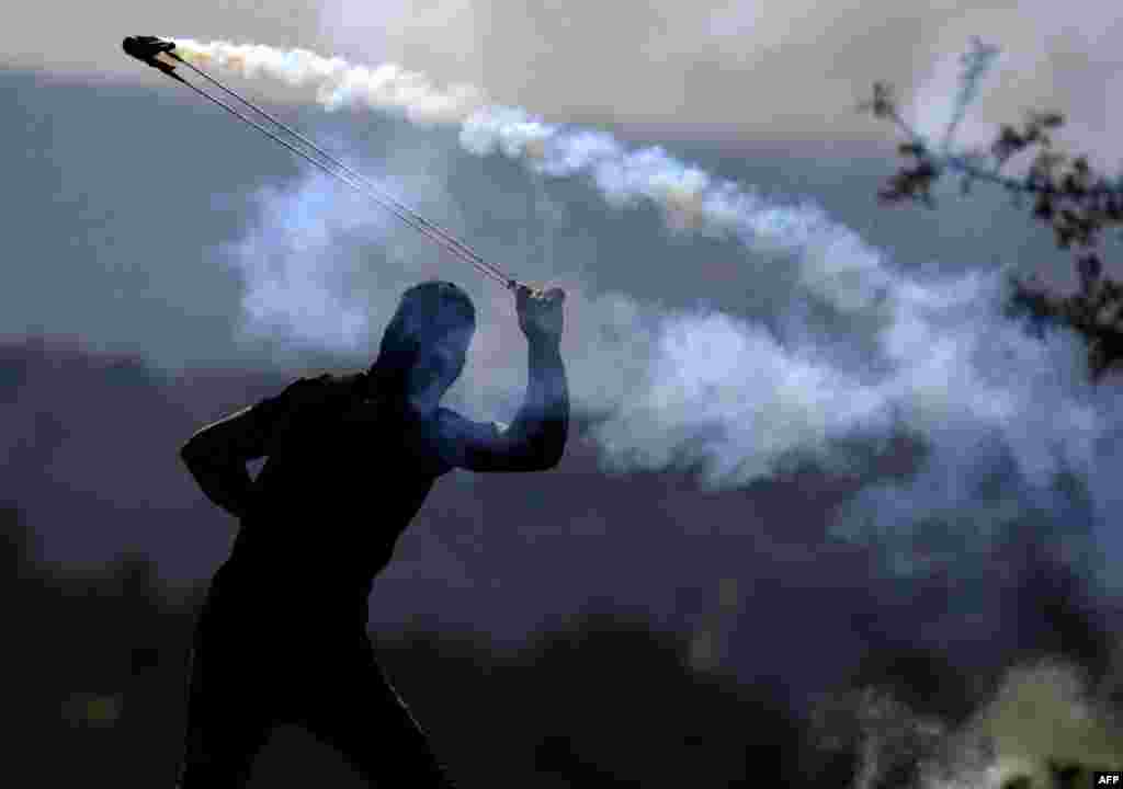 A Palestinian protester throws tear gas towards Israeli soldiers who fired it during a demonstration against Israeli land seizures for Jewish settlements in the occupied West Bank.