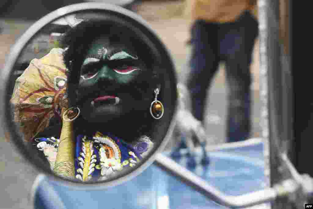 The reflection of a man dressed as Hindu deity of death Yamaraj, to raise awareness about the coronavirus, is seen on the wing mirror of a vintage car during a government-imposed nationwide lockdown, in Kolkata, India.
