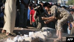Un présumé combattant du groupe Etat islamique détruit des objets anciens et un site du patrimoine mondial de l'Unesco situé au nord-est de Damas, dans la ville de Manbij, au nord-est d'Alep (transmise par la propagande islamiste média Welayat Halab à l’AFP, 2 juillet 2015).