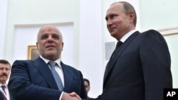 블라디미르 푸틴 러시아 대통령(오른쪽)과 하이데르 알아바디 이라크 총리가 21일 모스크바에서 회동해 악수하고 있다.