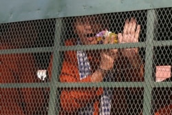 FILE - Member of the dissolved opposition Cambodia National Rescue Party (CNRP) Ouk Pich Samnang reacts inside a police vehicle on his way to attend a verdict announcement at the appeal court in Phnom Penh, Cambodia, May 10, 2018.