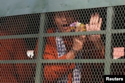 Ouk Pich Samnang, a member of the dissolved opposition Cambodia National Rescue Party (CNRP), reacts inside a police vehicle on his way to attend a verdict announcement at the appeal court in Phnom Penh on May 10, 2018. (Samrang Pring/Reuters)