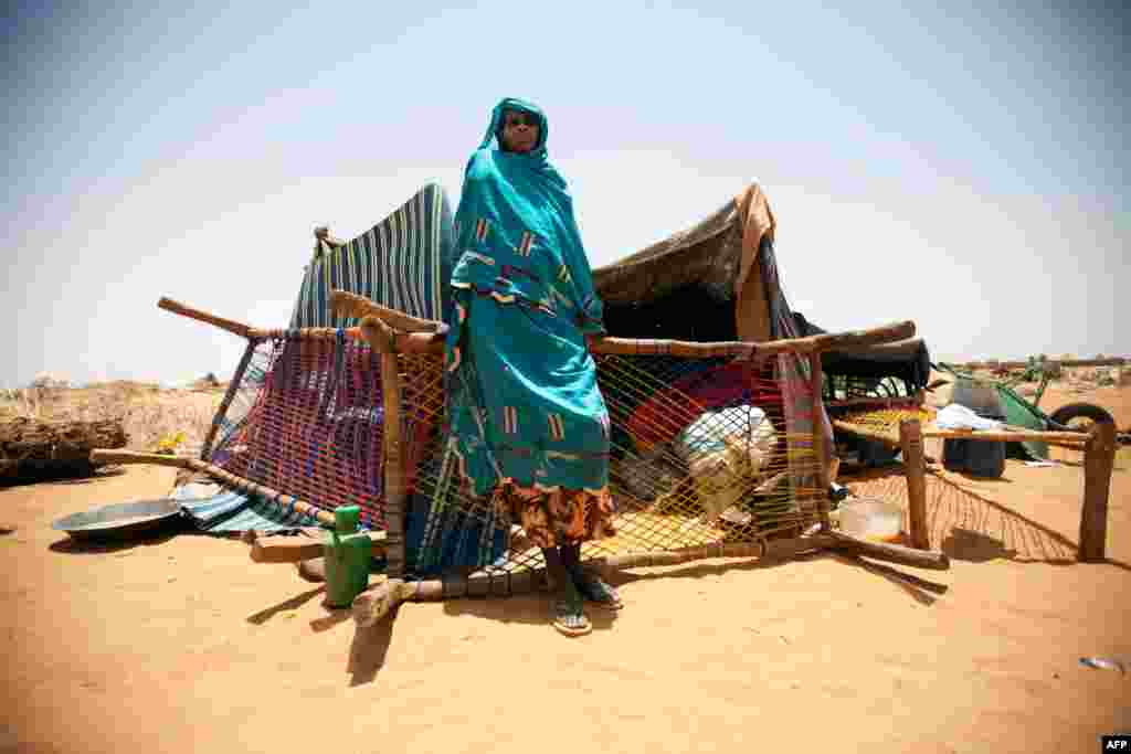 A handout picture released by the United Nations-African Union Mission in Darfur (UNAMID) shows a Sudanese woman standing in front of her shelter and belongings in the Zam Zam camp for Internally Displaced Persons (IDP), in North Darfur. 