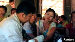 A government health worker takes a blood sample from a woman to be tested for malaria in Ta Gay Laung village hall in Hpa-An district in Kayin state, southeastern Myanmar, Nov. 28, 2014.