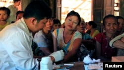 FILE - A government health worker takes a blood sample from a woman to be tested for malaria in Ta Gay Laung village hall in Hpa-An district in Kayin state, southeastern Myanmar, Nov. 28, 2014.