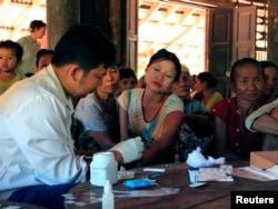 FILE - A government health worker takes a blood sample from a woman to be tested for malaria in Ta Gay Laung village hall in Hpa-An district in Kayin state, southeastern Myanmar, Nov. 28, 2014.