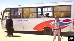 This image released by the Minya governorate media office shows a policeman and a priest next to a bus after militants stormed the bus in Minya, Egypt, May 26, 2017.