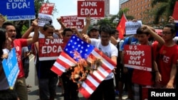 A protester holds a burning mock U.S. flag in condemnation of the strenghtened U.S. intervention under the Enhanced Defense Cooperation Agreement (EDCA) during a protest in front of the U.S. embassy in metro Manila, Philippines June 12, 2016. REUTERS/Romeo Ranoco 