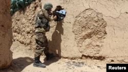 FILE - An Afghan National Army (ANA) soldier mans his position at an outpost in Babaji area of Lashkar Gah Helmand province, Afghanistan.