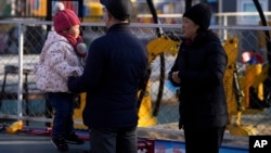 A couple watch a child jump on a trampoline at an amusement park in Beijing, China, Jan. 17, 2022. The number of babies born in China continued to shrink last year in a decade-long trend, official data shows.