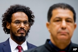 Ahmad Al Mahdi Al Faqi, left, enters the court room for his initial appearance at the International Criminal Court in The Hague, Netherlands, Sept. 30, 2015.