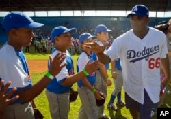 Los Angeles Dodgers player Yasiel Puig, from Cuba, greets young baseball players before giving a clinic in Havana, Cuba, Dec. 16, 2015. It was the first Major League Baseball trip to the island since 1999.