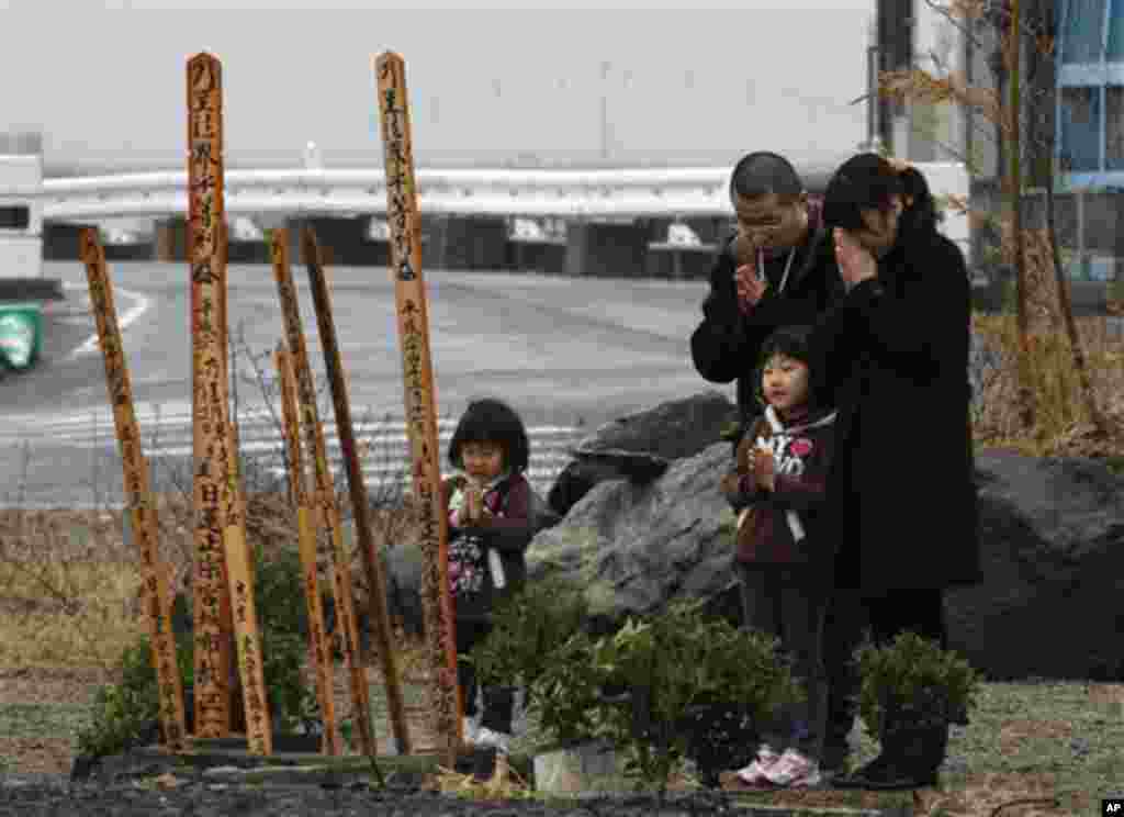A family offers prayers at a makeshift shrine in a neighborhood devastated by a tsunami in Natori, Miyagi Prefecture, northern Japan, Saturday, March 10, 2012 on the eve of the first anniversary of the disaster. (AP Photo/Shizuo Kambayashi)