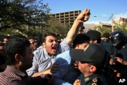 An Iranian protester chants slogans while police officers prevent him from approaching to the Saudi Arabian Embassy in Tehran, Iran, Sept. 27, 2015, during a gathering to blame the Arab country for a deadly stampede.