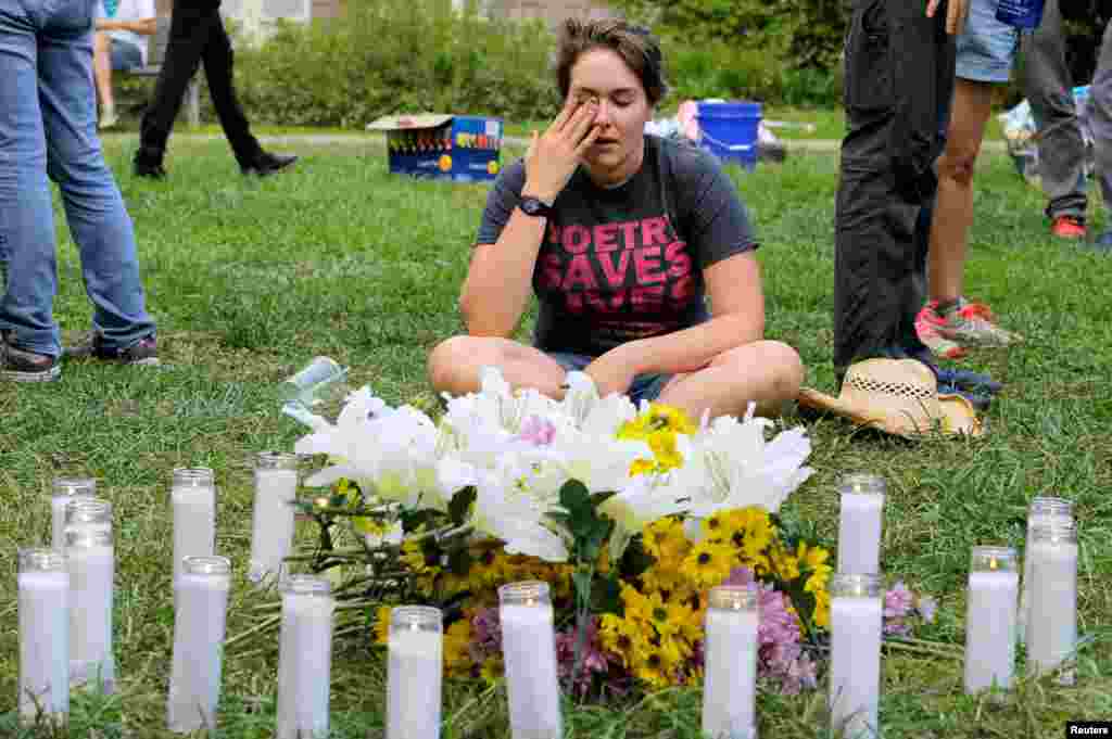A local resident of Charlottesville wipes tears from her eyes at a vigil where 20 candles were burned for the 19 people injured and one killed when a car plowed into a crowd of counter protesters at the &quot;Unite the Right&quot; rally organized by white nationalists in Charlottesville, Virginia, Aug. 12, 2017.