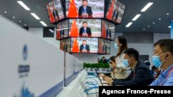 FILE - Media staff work next to screens showing live images of China's President Xi Jinping speaking during the opening ceremony of the China International Import Expo in Shanghai on Nov. 4, 2021.