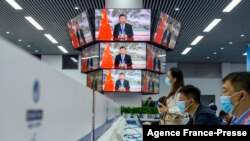 ARCHIVO - El personal de los medios trabaja junto a las pantallas que muestran imágenes en vivo del presidente de China, Xi Jinping, hablando durante la ceremonia de apertura de la Exposición Internacional de Importaciones de China en Shanghái el 4 de noviembre de 2021.