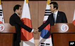 South Korean Foreign Minister Yun Byung-se, right, shakes hands with Japanese counterpart Fumio Kishida after a joint press conference in Seoul, South Korea, Dec. 28, 2015.